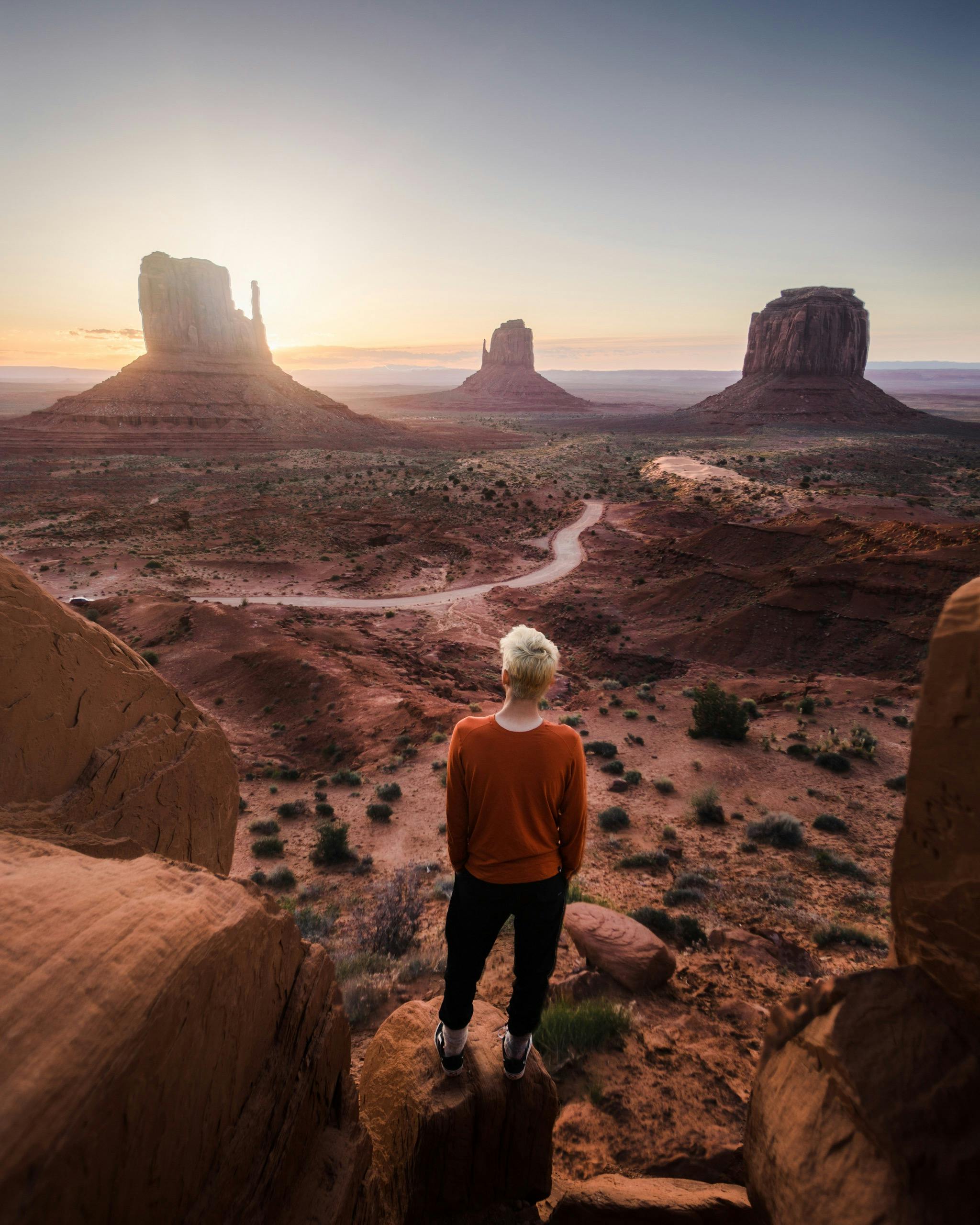 A person overlooks Monument Valley at sunrise, capturing a stunning landscape view.