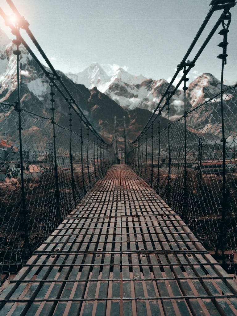 Breathtaking view of a suspension bridge leading to the snowy Himalayan mountains in Nepal.